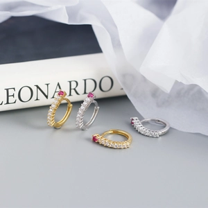 Close-up of S925 silver hoop earrings with red gemstone and sparkling row of zircons