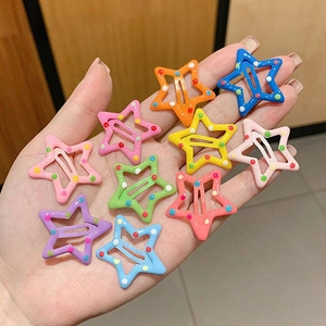 Detail of colorful star-shaped hair clips with polka dots held in hand for children
