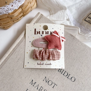 Detail of pink felt star and checkered fabric hair clips set on a rustic background