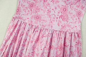 Gros plan sur la taille plissée haute et l'imprimé floral de cette robe rose ligne A