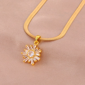 Macro detail of a gold snake chain necklace with a sparkling zircon sunflower pendant