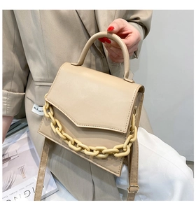 Detail of beige PU crossbody bag with unique asymmetric flap and matte chain strap