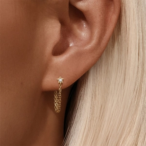 Detail of gold star earring with chain tassel and sparkling crystal inlay for women
