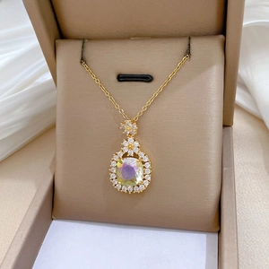Macro detail of gold-plated pendant with rainbow gem and sparkling pavé crystals