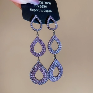 Detailed macro view of triple-layered purple drop earrings with sparkling crystals
