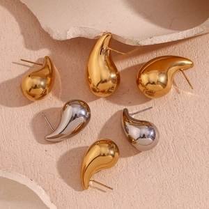 Detailed view of teardrop earrings in gold and silver finish with high-polish metallic texture