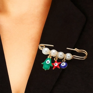 Détail d'une broche épingle à nourrice dorée avec perles et œil bleu sur un costume noir