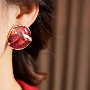 Close-up of a large vintage red enamel stud earring with gold-tone irregular wavy border