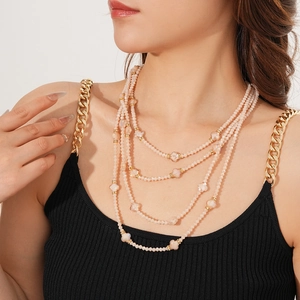 Détail d'un collier de perles roses multicouches avec accents de fleurs dorées