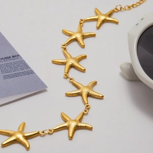 Elegant gold starfish charm bracelet with freshwater pearls on a fashion magazine background