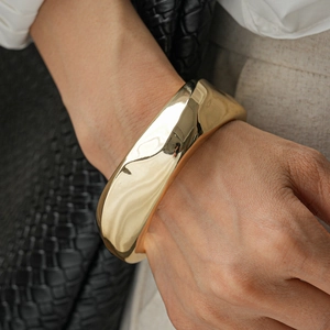 Detailed view of wide gold irregular wave cuff bracelet worn on model with elegant styling