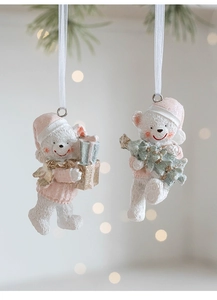 Close-up of cute resin Christmas bears wearing pink sweaters and hats on festive branches
