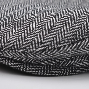 Macro shot of gray herringbone textured fabric detail for men's casual beret flat cap