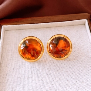 Detail of amber resin earrings with golden metal borders in a premium wood jewelry box