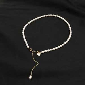 Natural freshwater pearl necklace with golden heart pendant on black silk background
