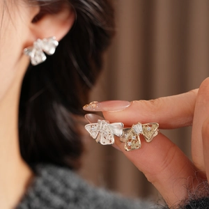 Détail de boucles d'oreilles nœud creux en finitions argent et or avec zircons brillants