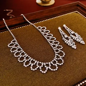 Set collana con frange di strass e orecchini geometrici a goccia su espositore verde