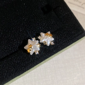 Détail de boucles d'oreilles étoile avec nacre et petites étoiles dorées serties de zircons