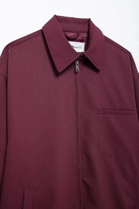 Detail of burgundy zip-up jacket with pocket and MWOMAN label in high quality fabric
