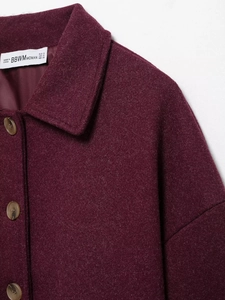 Detailed close-up of burgundy wool coat lapel, button, and fabric texture with size tag