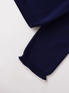 Detail eines dunkelblauen Strickpullovers mit Rippbündchen und weißem Spitzenbesatz