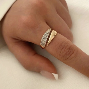 Detailed close-up of a golden open ring featuring pavé diamonds and a polished teardrop end