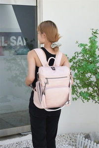 Close-up of pink backpack with fringe detail and geometric woven shoulder strap