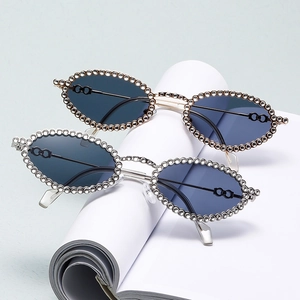Oval rhinestone sunglasses with metal frames in gold and silver colors on white paper