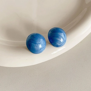 Detailaufnahme der blauen runden Ohrstecker mit Marmoreffekt auf Keramikschale