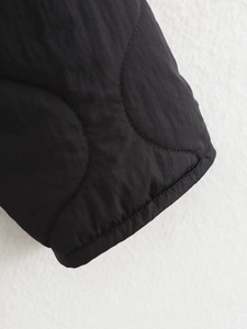 Detail of wave-quilted black jacket sleeve showing quality stitching and fabric texture