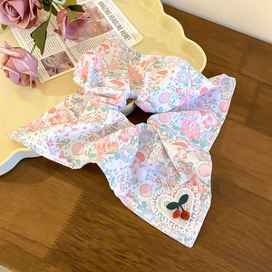 Détail d'un chouchou floral avec nœud, patch cœur en dentelle et décor de cerises