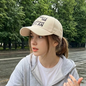 Vintage beige cotton baseball cap with black embroidery shown on a model in outdoor setting