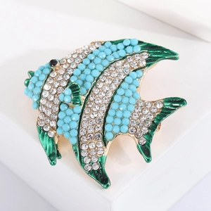Macro shot of tropical fish brooch with blue beads and green enamel on gold alloy