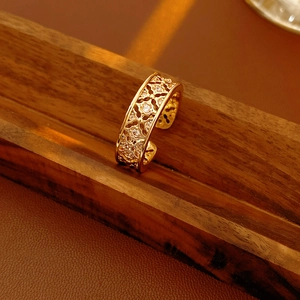 Macro detail of gold plated flower ring with cubic zirconia on walnut wood