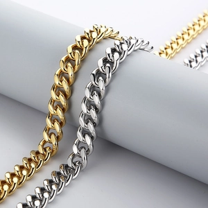 Close-up of polished gold and silver Cuban link chains wrapped on a gray stand
