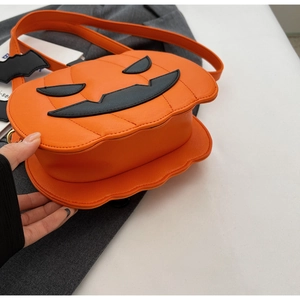 Close-up of orange pumpkin bag with black bat wings and textured saffiano leather surface