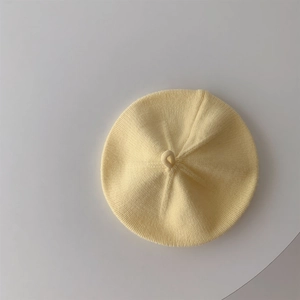 Close-up of baby knit beret in cream yellow showing soft textured fabric detail