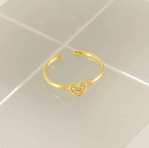 Detailed shot of a gold open ring featuring a heart shape set with three zircon stones