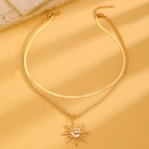 Close-up of golden double-layer necklace with sun ray pendant and twisted chain link