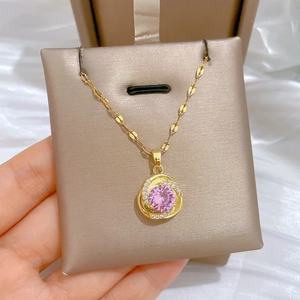 Macro shot of gold pendant with large pink gemstone and sparkling white diamonds