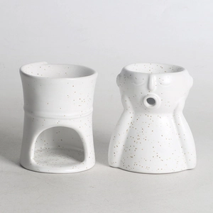 Minimalist white ceramic oil burner with spotted pattern and abstract facial statue design