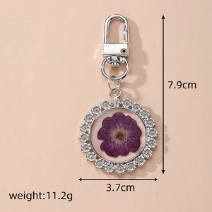 Detailed view of dried flower keychain with purple daisy and silver metallic shell frame