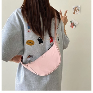 Detailed side view of a pink nylon crescent crossbody bag worn by a model in casual style