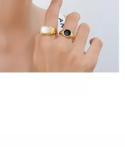 Close-up of dual gold rings set with pearl shell and black enamel inlay worn on finger