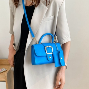Retro vibrant blue crossbody bag with gold buckle and matching coin purse on grey blazer