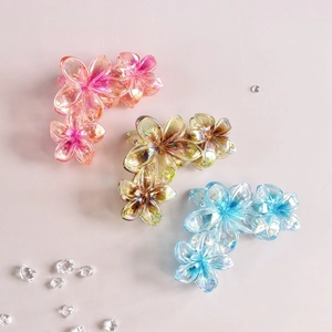Close-up of three iridescent flower-shaped hair claws in pink, yellow and blue colors