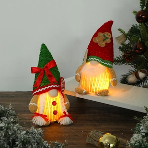Lighted Christmas gingerbread gnomes in red and green festive hats on a wooden desk