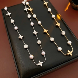 Detail of gold and silver flower pearl necklaces with zircon clover pendants on a display