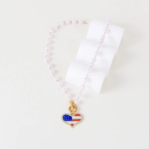 Detailed view of heart-shaped USA flag pendant with pink pearls and rhinestone inlay