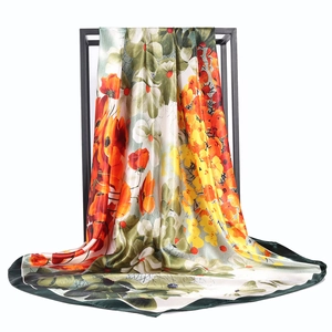 Carré de soie imprimé floral 90x90cm orange et vert suspendu sur un support en métal noir